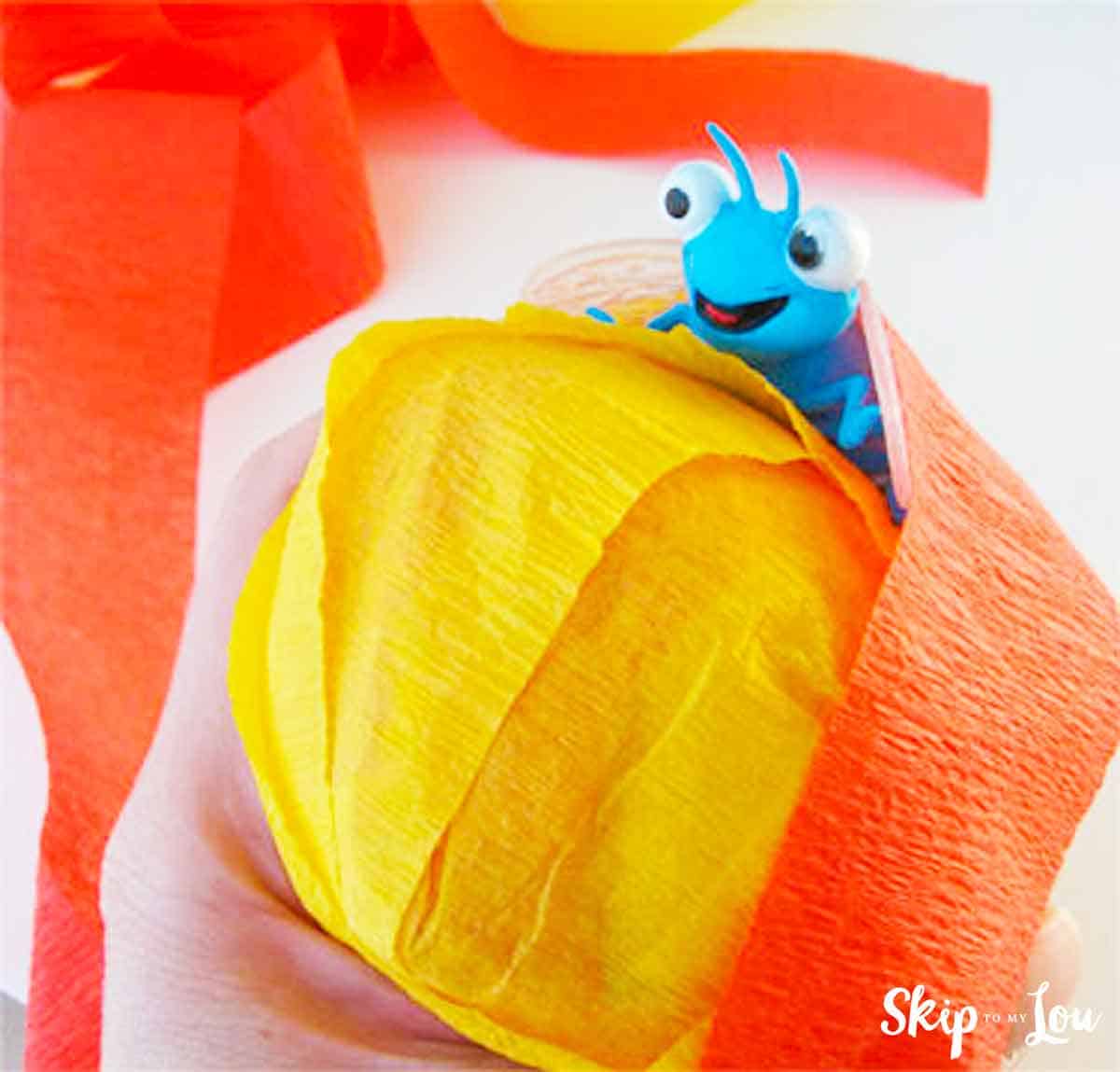 Surprise ball made with orange and yellow crepe paper with a blue toy ant
