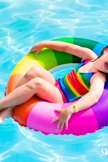 girl in rainbow water toy smiling water jokes