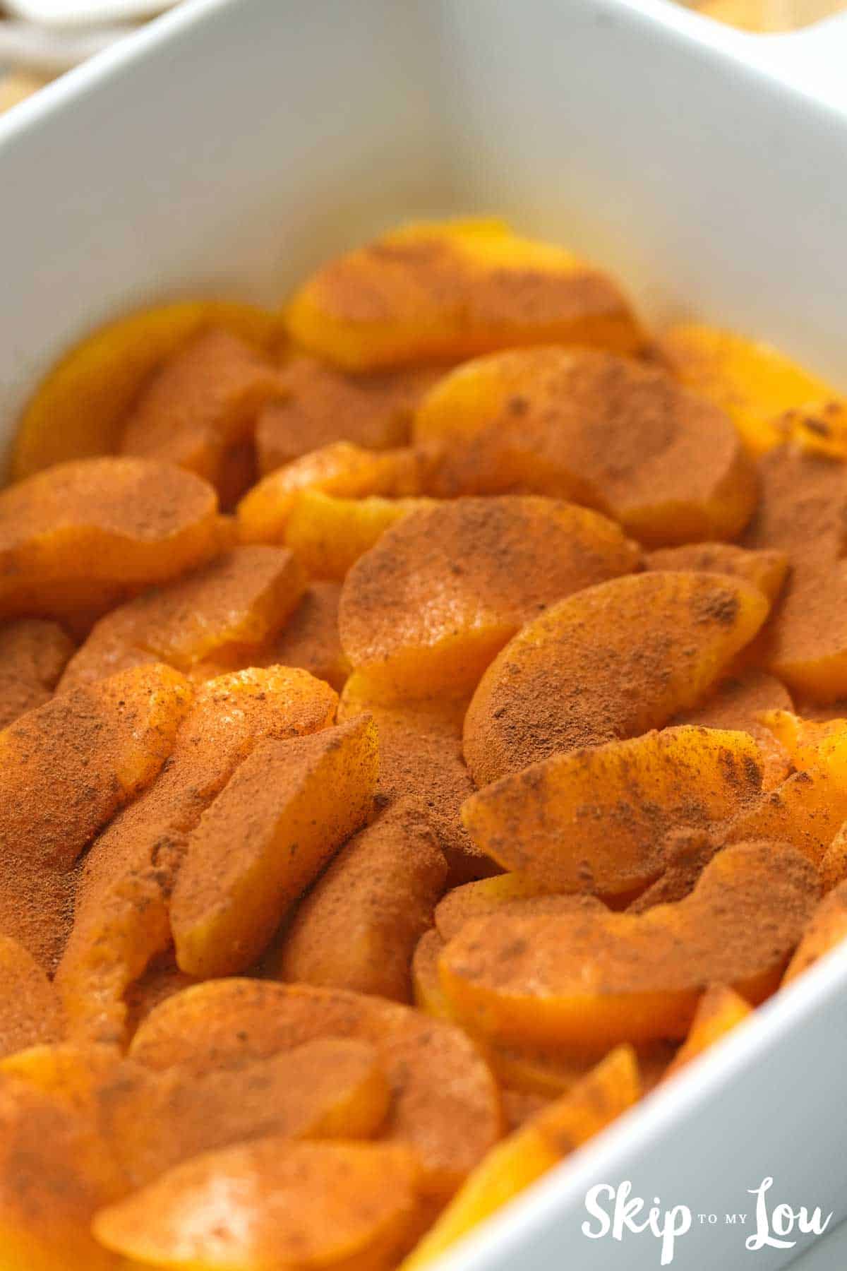 cinnamon on peaches in white baking dish