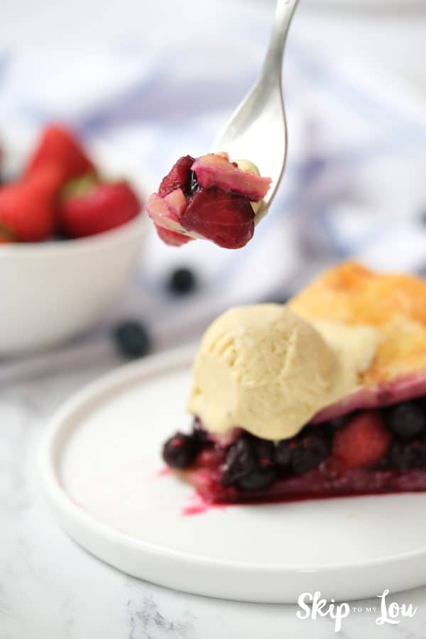 Triple Berry Pie with bite on fork served with vanilla ice cream.