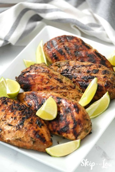 Jerk Chicken served on a white dish with lemon quarters. -Skip To My Lou