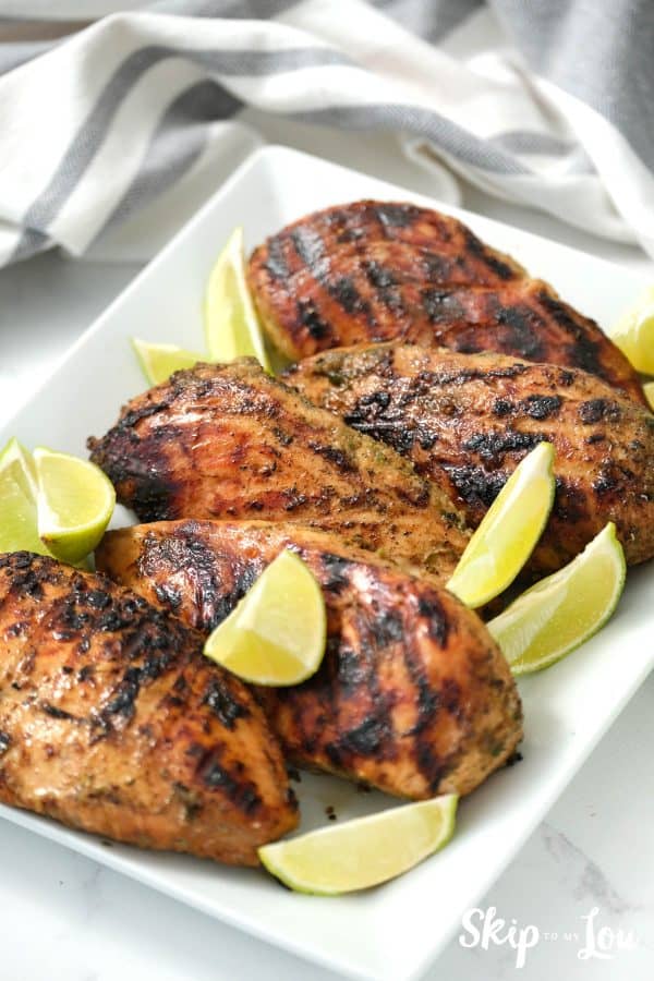 Jerk Chicken served on a white serving dish garnished with limes. -Skip To my Lou