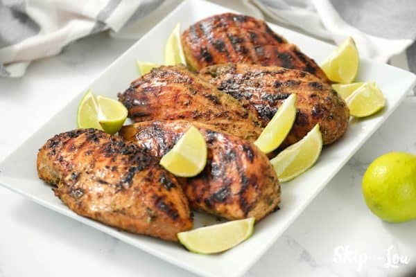 Jerk Chicken served on a white serving dish with lemon quarters. -Skip To My Lou