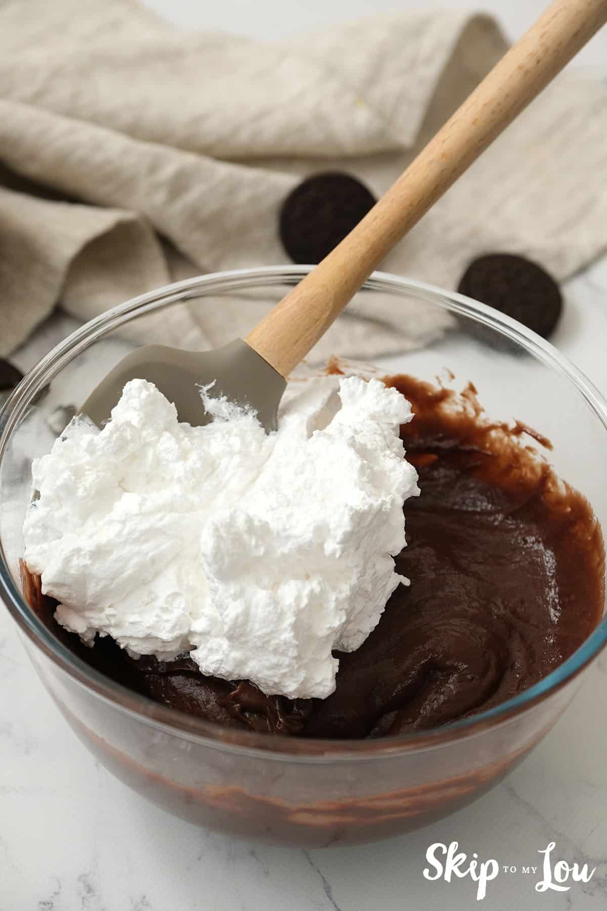 Cool whip on top of chocolate pudding about to be stirred in for the Oreo Pie.