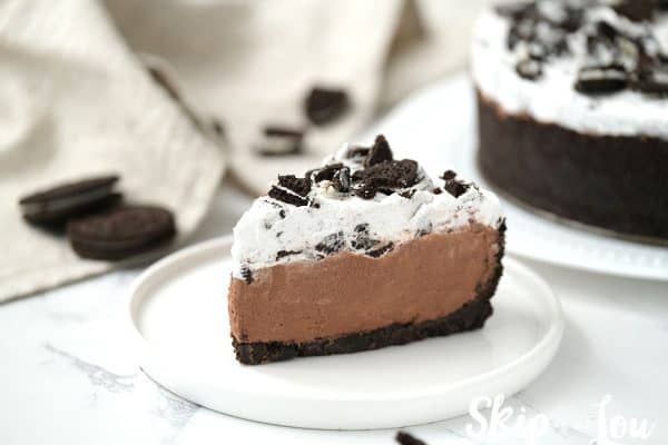 Slice of the Oreo Pie served on a white dish and the Oreo Pie in the background.