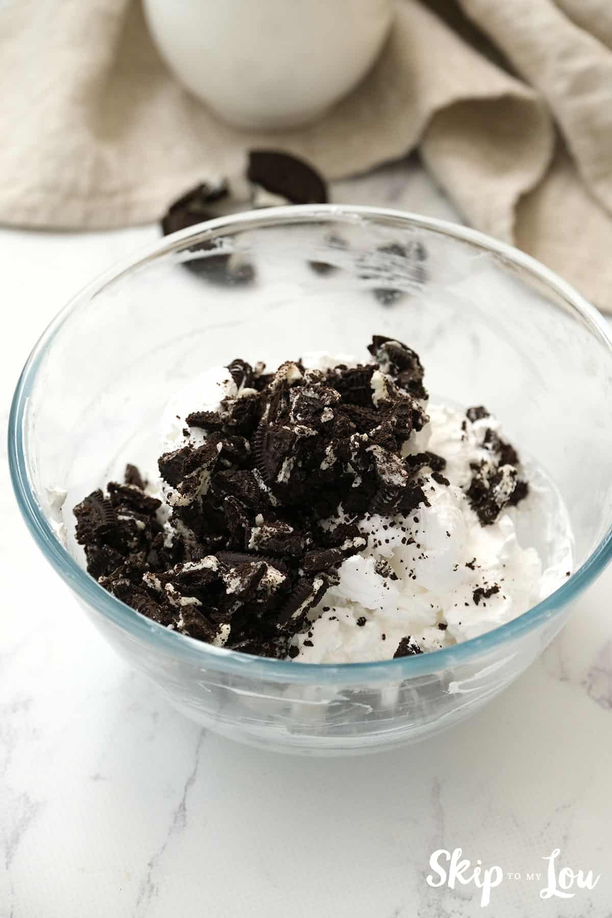 A bowl with chopped Oreo cookies and cool whip for topping the Oreo Pies