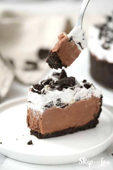 A slice or Oreo Pie served on a white dish and a bite on a fork.