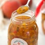 Jar of Peach Salsa with the lid off and a spoonful being taken out. Cute label on jar Homemade Peach Salsa