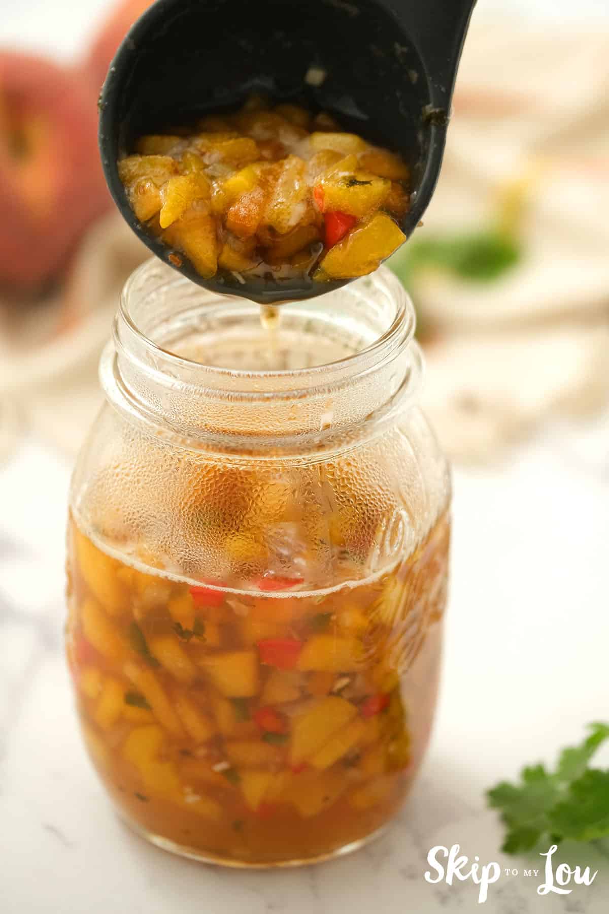 Peach Salsa being poured into canning jar.