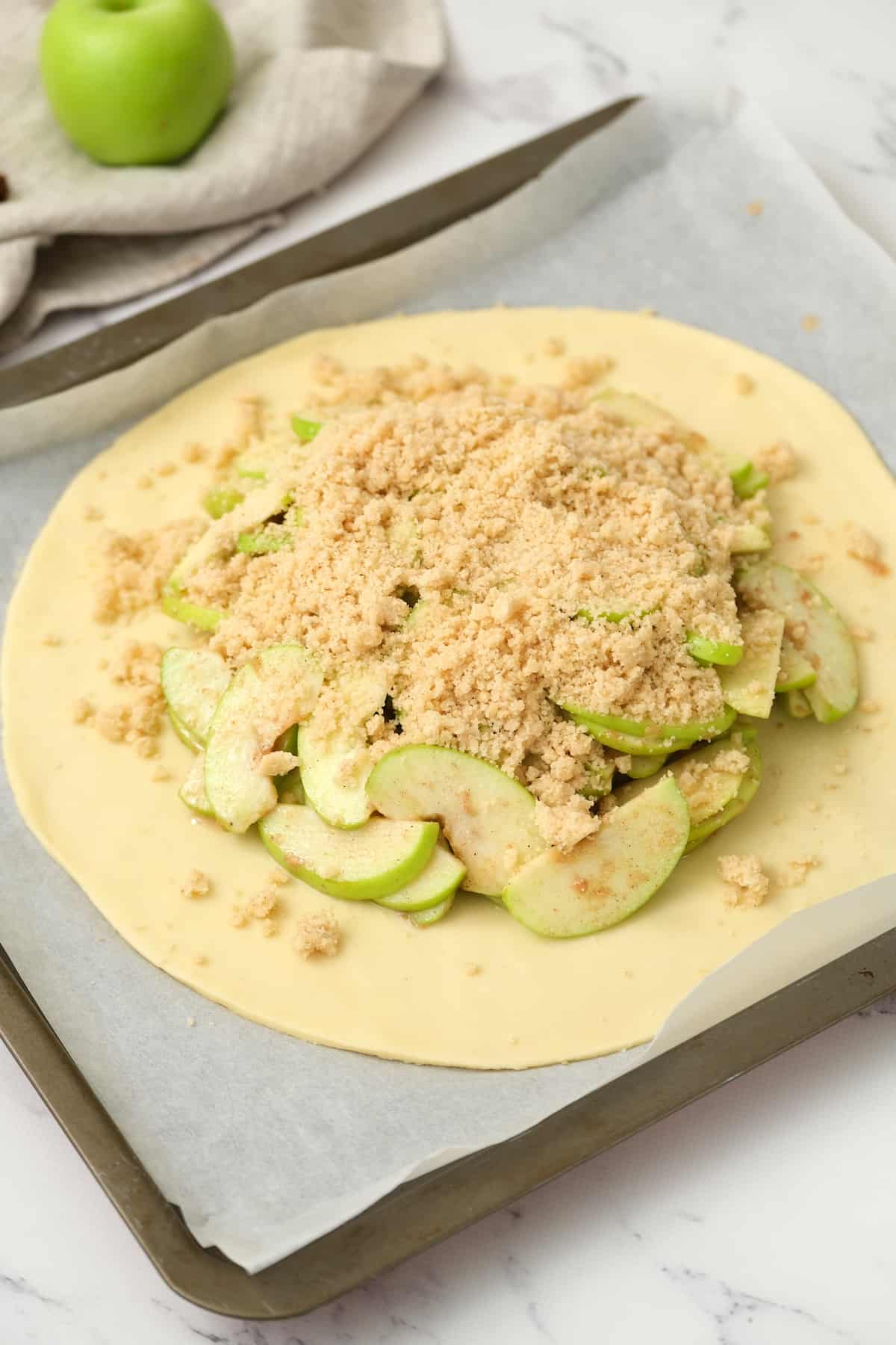 Rustic apple pie topping sprinkled on top of the apples .