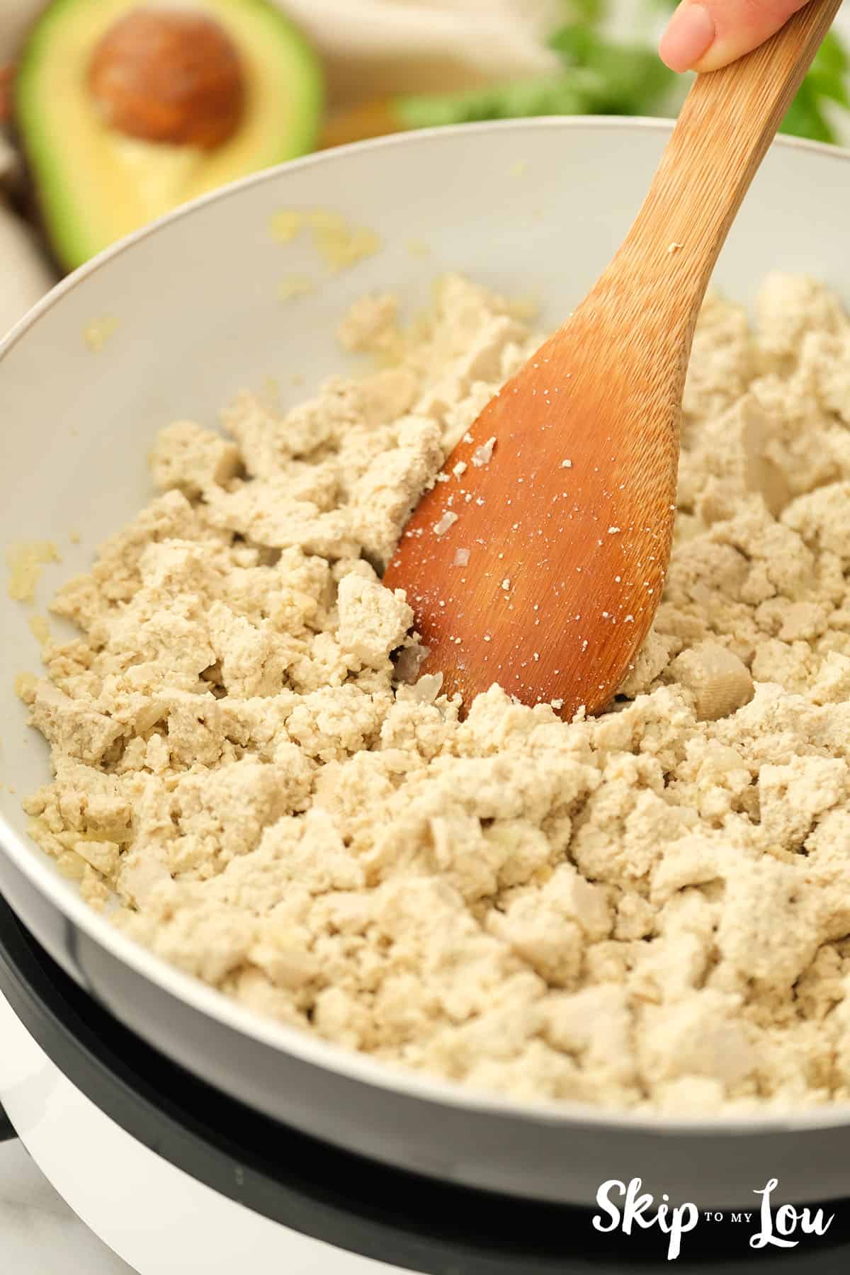 Tofu added to the large pan with the onion cooked and crumbled into pieces for the sofritas bowl