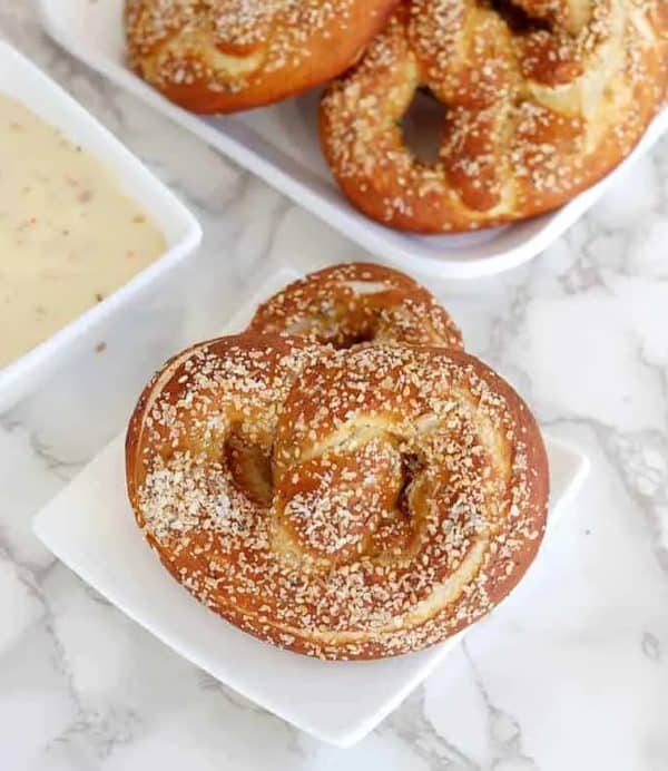 Image shows a sourdough pretzel on a small white plate.