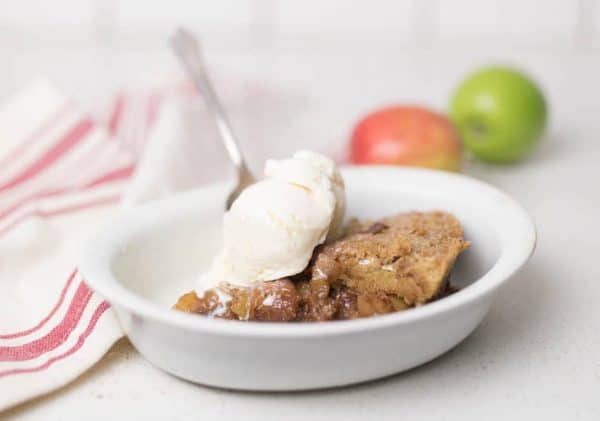 Image shows a cinnamon maple sourdough apple pie served with ice cream on top.
