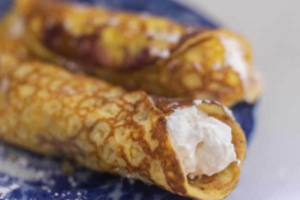 Image shows two sourdough crepes on a blue plate, filled with creme.