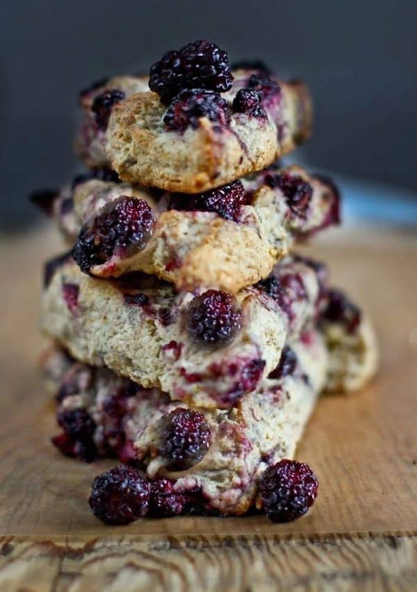 Image shows a pile of sourdough scones with lemony glaze over a wooden table.