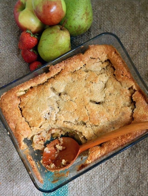 Image shows a glass container with a simple sourdough cobbler, a part of the cobbler is missing.