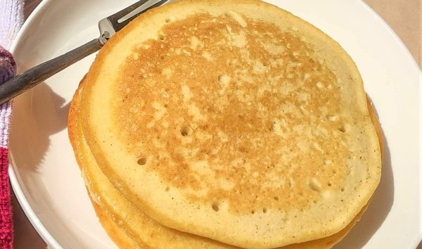Image shows three sourdough pancakes staked on top of each other on a plate.