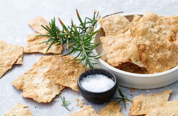 Image shows a plate filled with sourdough crackers with some herbs next to them, as well as sauce.