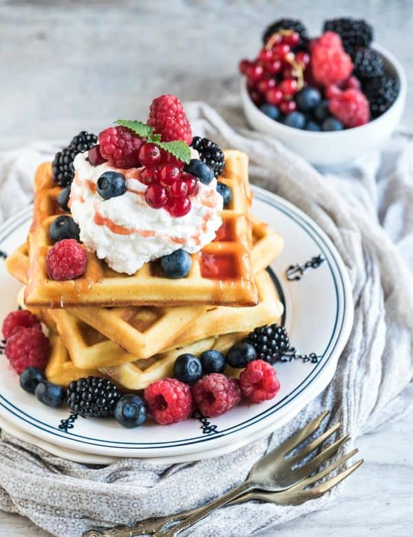 Image shows a pile of sourdough waffles with blueberries on top.