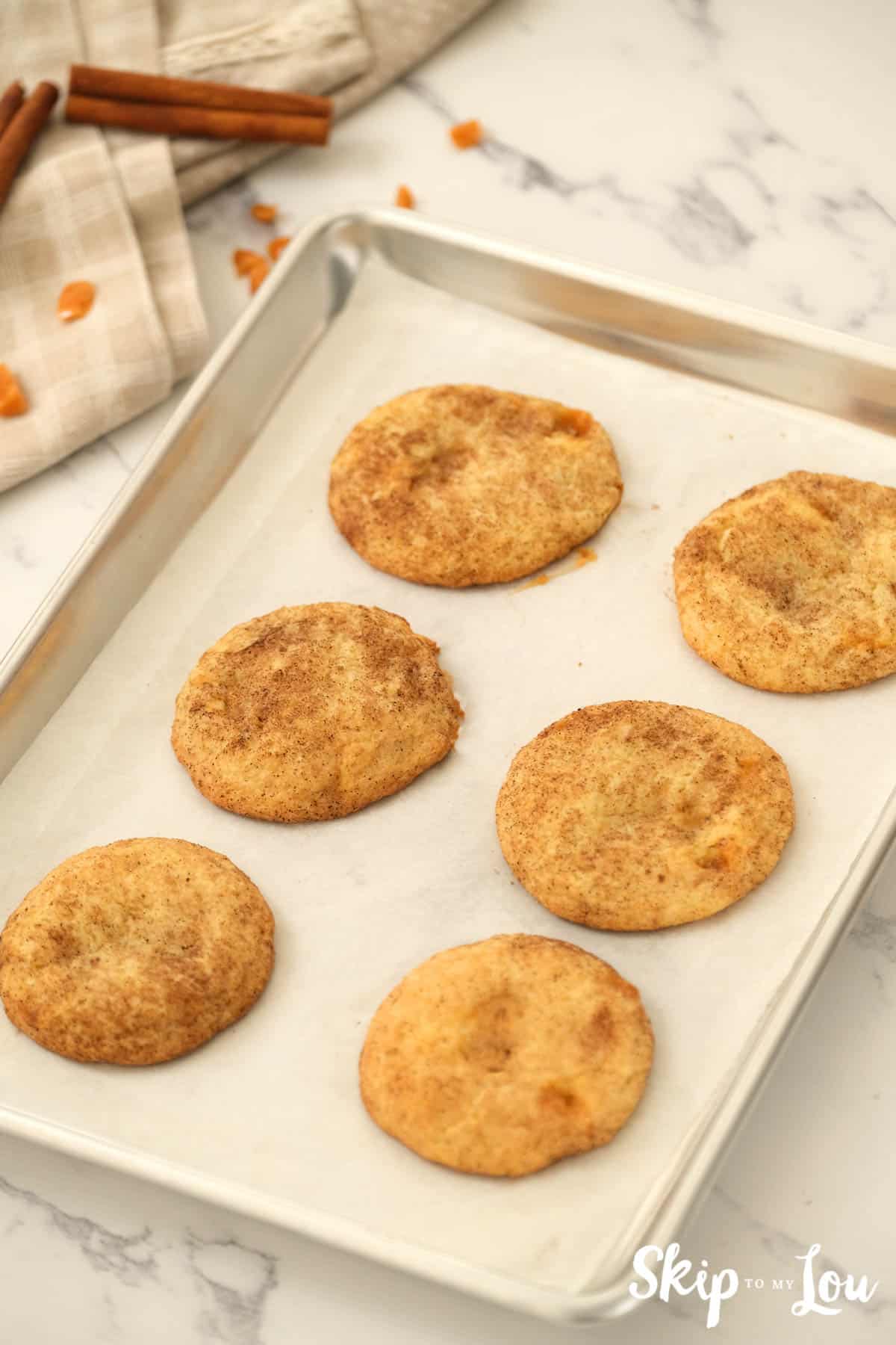 Baked Toffee Doodle Cookies on a parchment paper covered cookie sheet. -Skip To My Lou