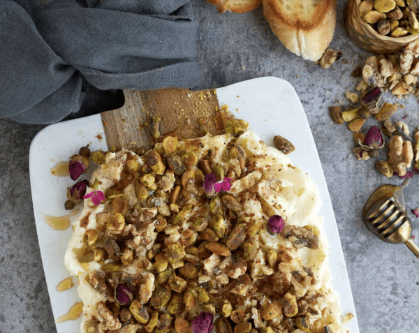 Image shows a baklava butter board with bread and nuts next to it.