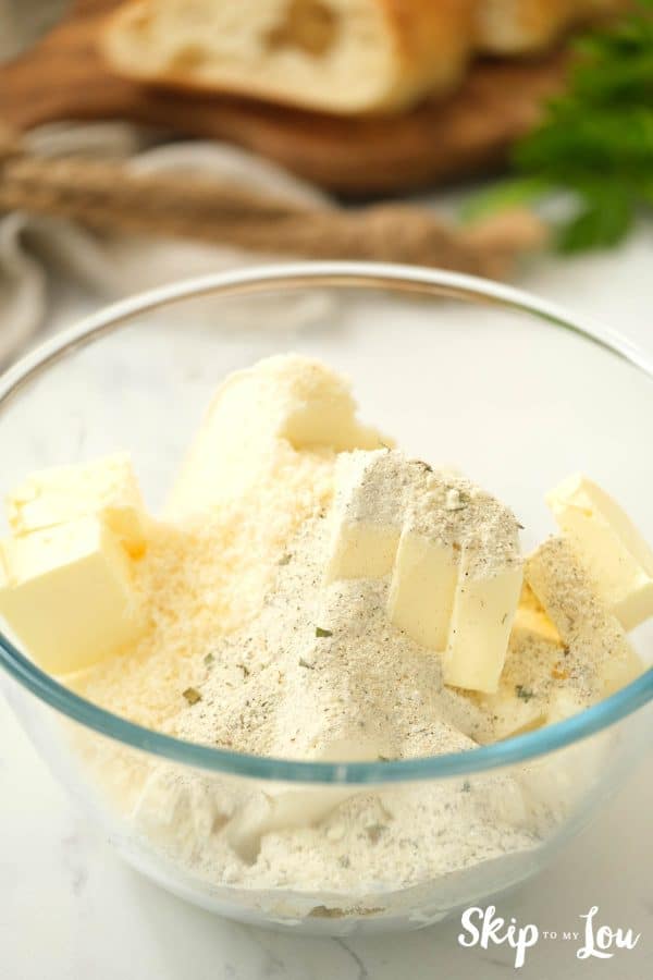 Glass mixing bowl with butter, cream cheese, dressing mix, and parmesan cheese. Herb Butter Cheese Spread -Skip to My Lou