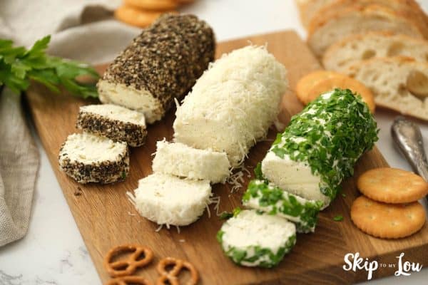Herb butter cheese spread sliced and served on a wooden board with pretzels and crackers. -Skip To My Lou