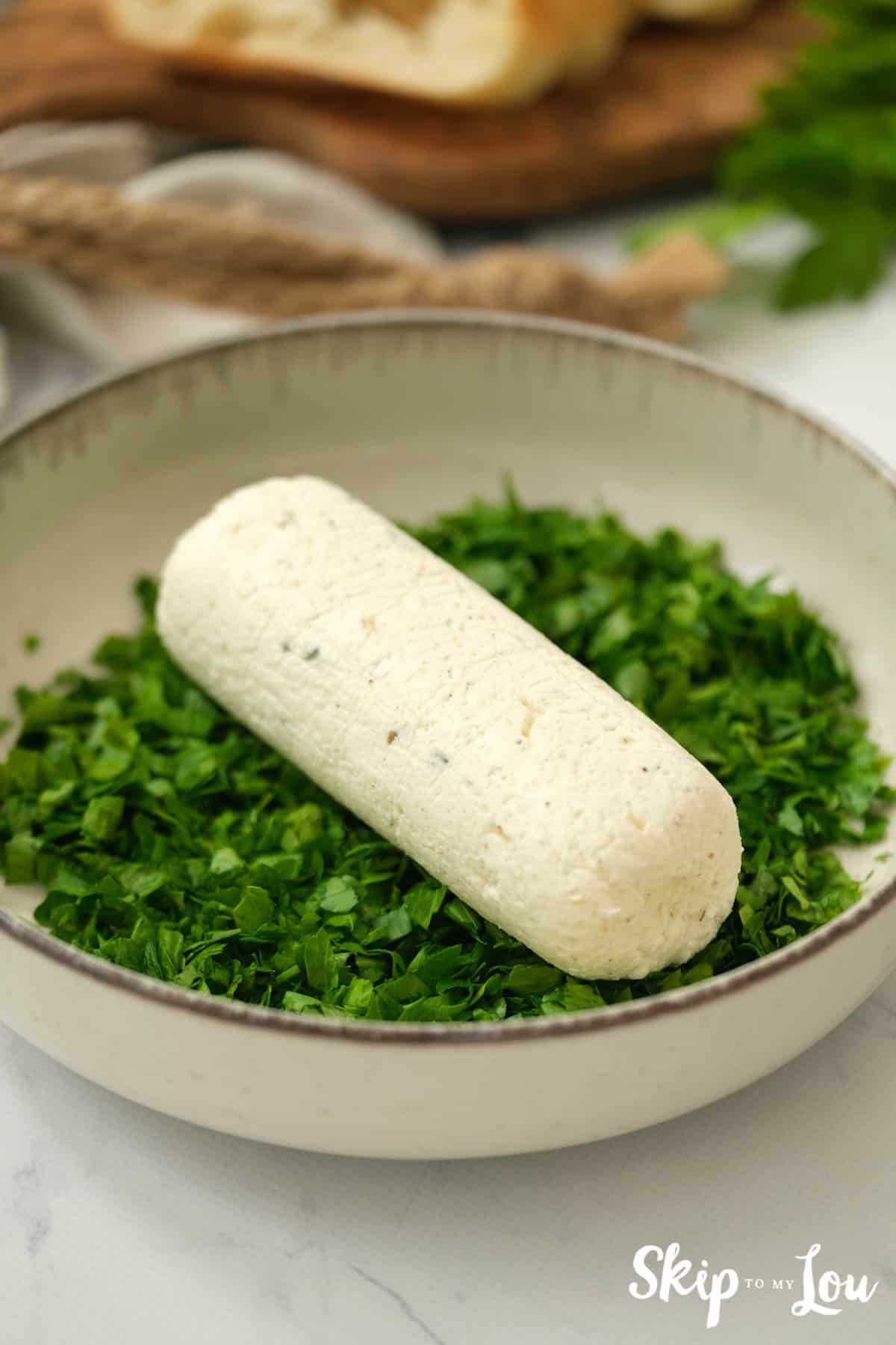 Herb Butter spread log in dish of chopped parsley. -Skip To My Lou