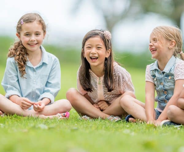 skip to my lou image of three kids sitting on grass laughing at kids jokes