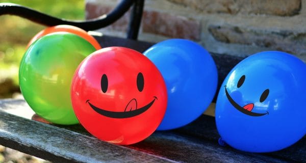 skip to my lou image of smiling emoji face balloons on a bench laughing at kids jokes