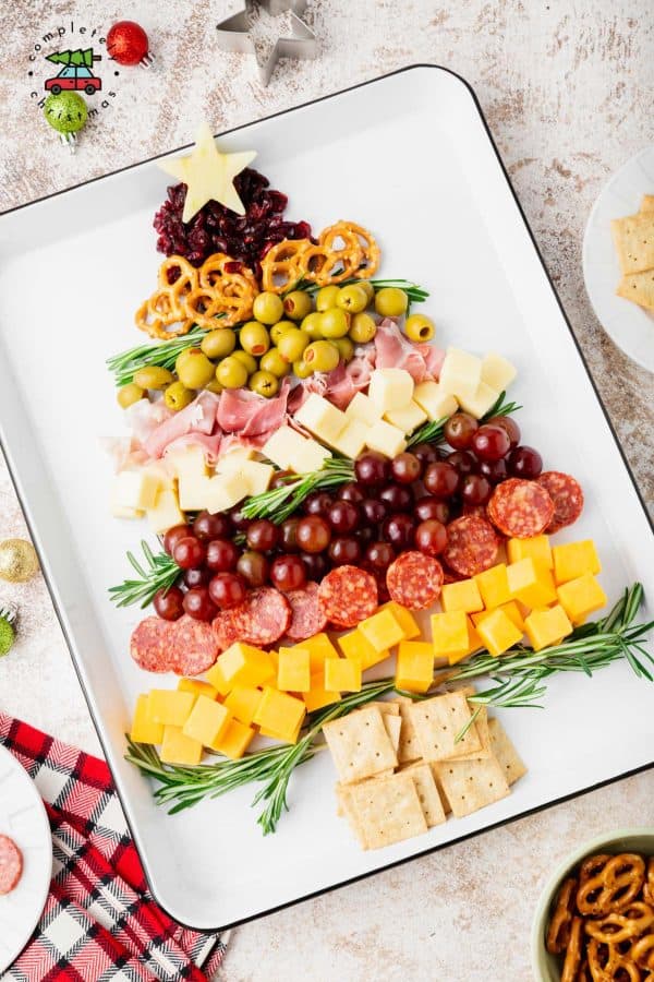 Image shows a charcuterie board with fruits and olives shaped like a Christmas tree. via completely christmas