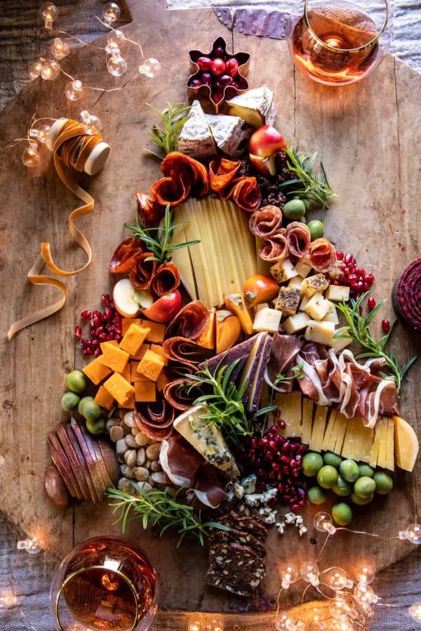 Image shows a charcuterie board with meats, cheeses, fruits, and vegies, decorated with Christmas decor. from half-baked harvest