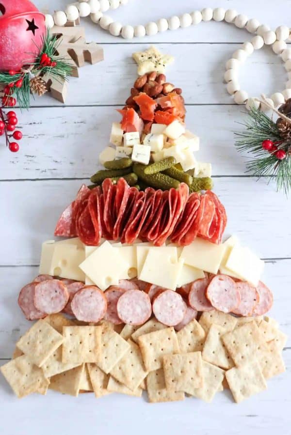 Image shows a charcuterie board with cheese, hams, pickles and nuts, shaped like a Christmas tree. via Homemade heather.