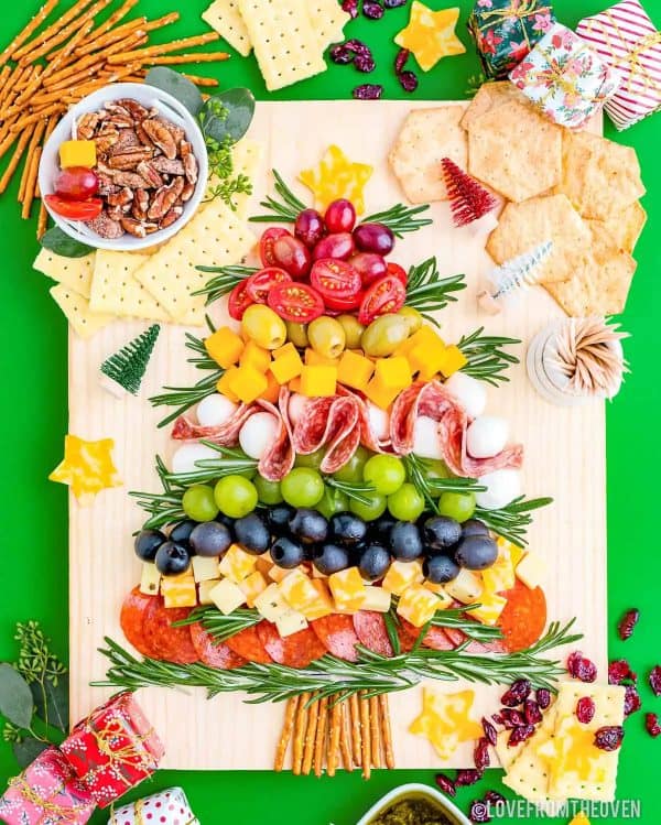 Image shows a Christmas charcuterie board with meats, cheeses, grapes, nuts and crackers. from Love from the oven.