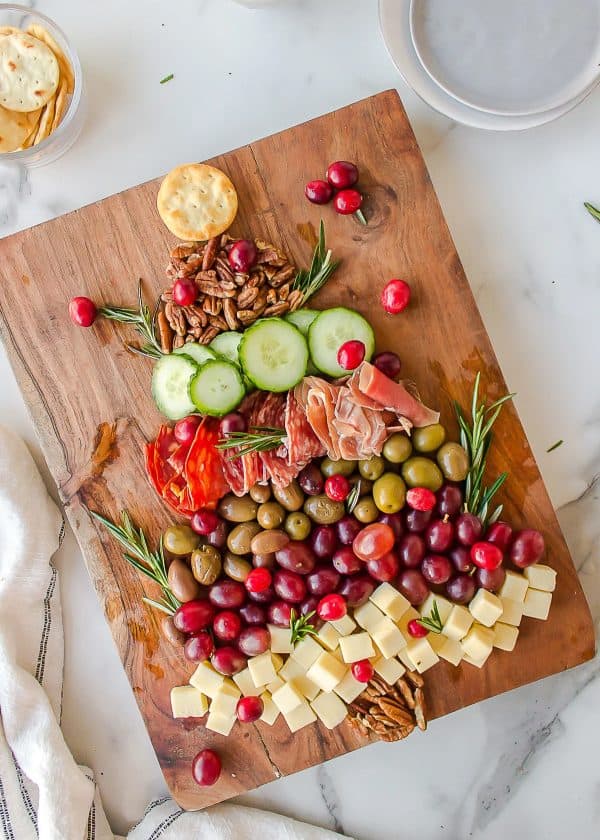 Image shows a charcuterie board with olives, grapes, cheese, alami,cucumber and nuts. via more than meats and potatoes