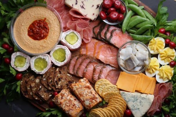 Image shows a charcuterie board with meats, crackers, hummus and vegetables. via snowflakes and coffeecakes.
