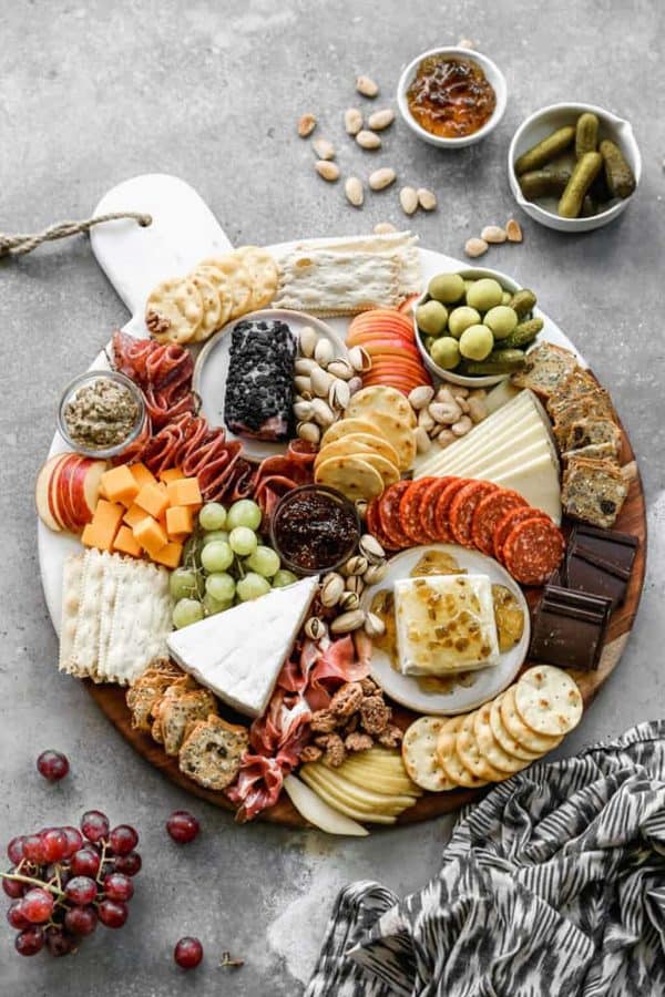 Image shows a charcuterie board with a christmas theme, it includes meats, cheeses, and chocolates. via tastes better from scratch