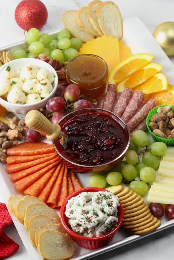 Image shows an appetizer tray is filled with plenty of meats and cheeses, plus seasonal flavors like cranberry sauce, candied nuts, and orange slices. via The Toasty Kitchen.