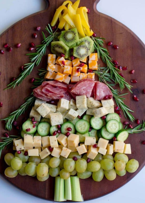 Image shows a charcuterie board with cheeese, meats, fruits and vegetables shaped like a christmas tree. via wholesomelicious