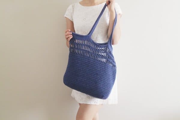 woman in white dress holding a purple totebag skip to my lou