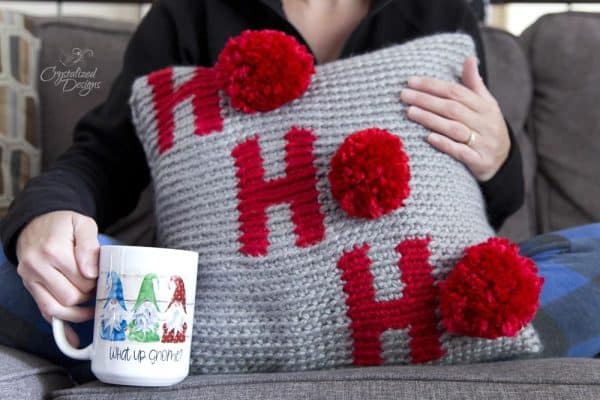 Gray crochet ho ho ho christmas pillow with red pom poms