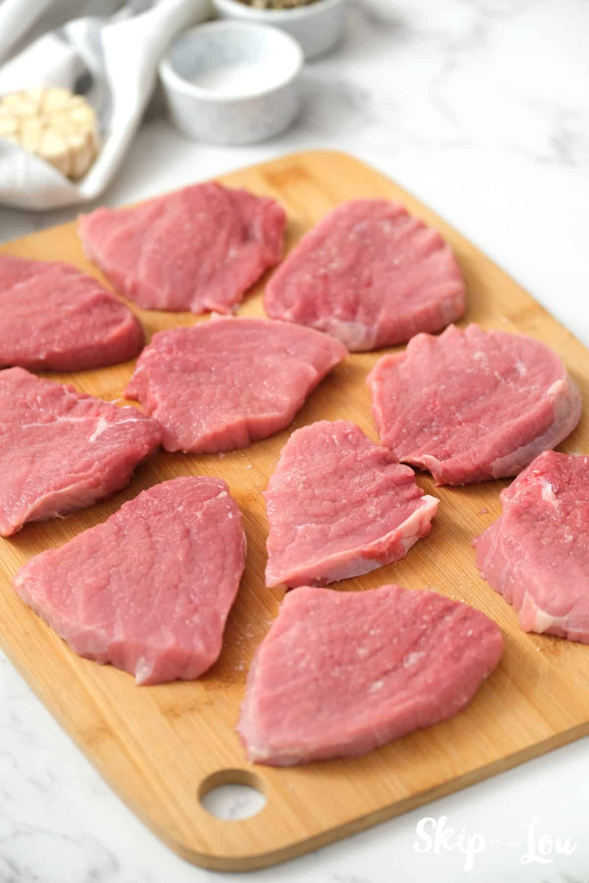 Bottom round steak slices on a cutting board for making the Swiss Steak Recipe. -Skip To My Lou