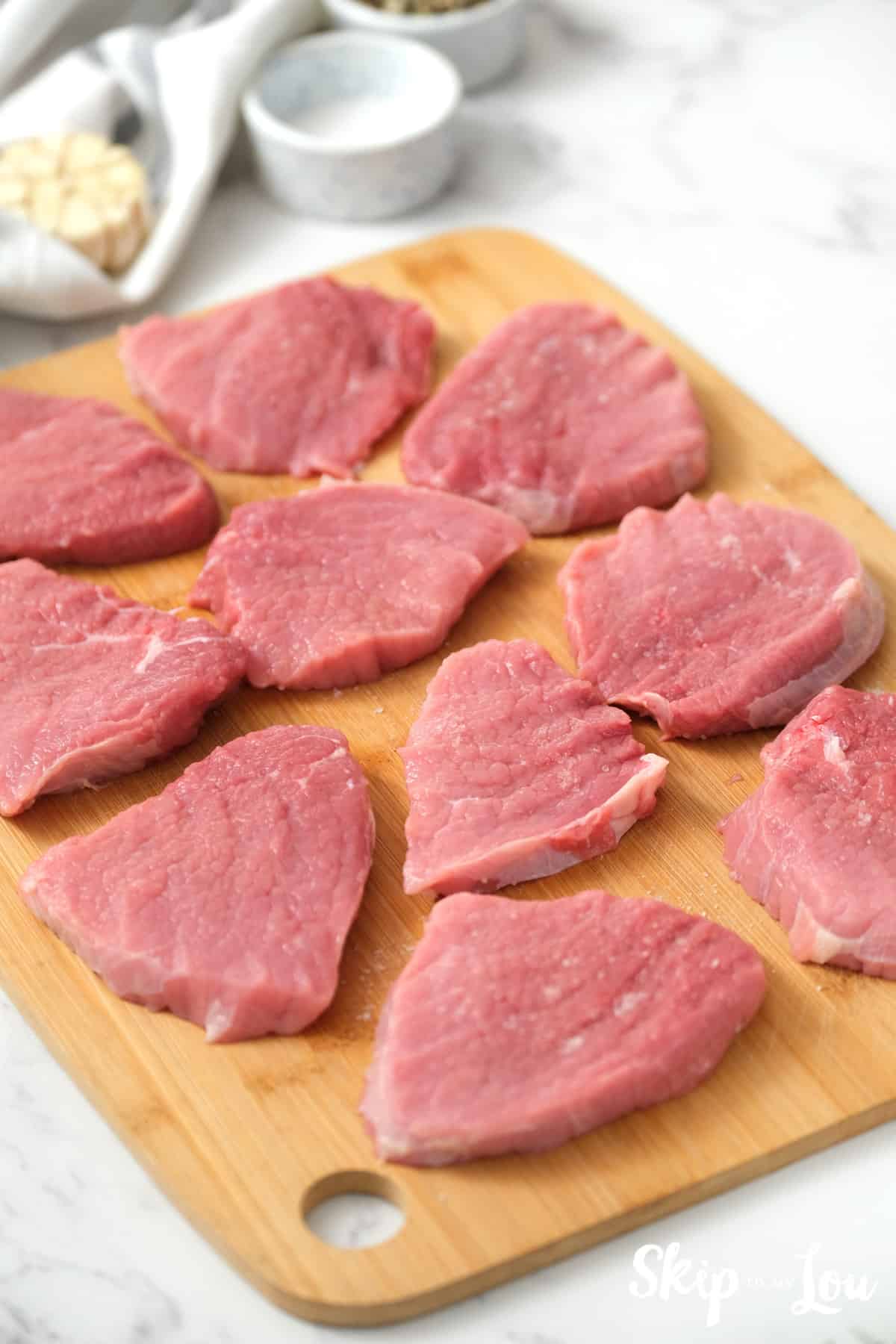 Bottom round steak slices on a cutting board for making the Swiss Steak Recipe. -Skip To My Lou