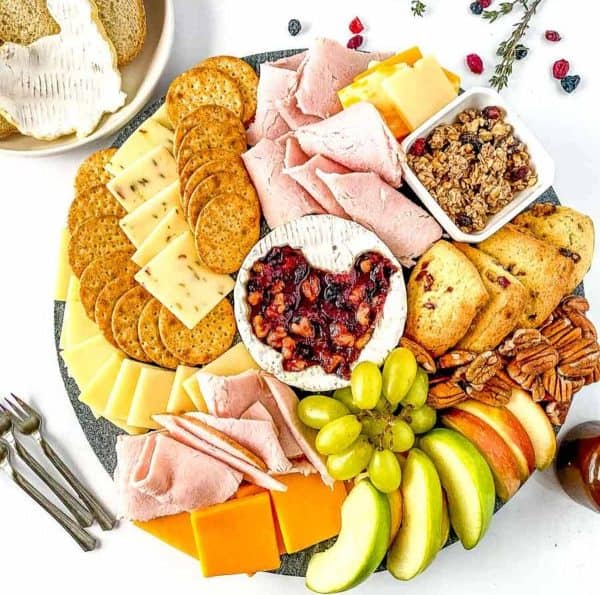 Image shows a Fall/Thanksgiving themed charcuterie board on a white table.