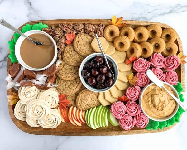 Image shows a Fall dessert board with dips, apple slices, doughnuts and more.