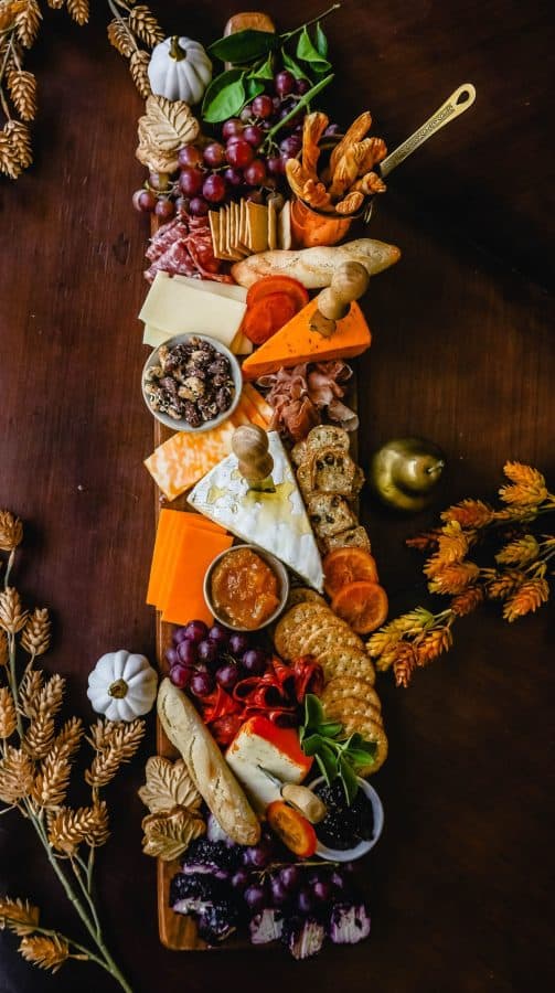 Image shows a large thanksgiving charcuterie board with cheese ,crackers, and decorated with Fall elements.