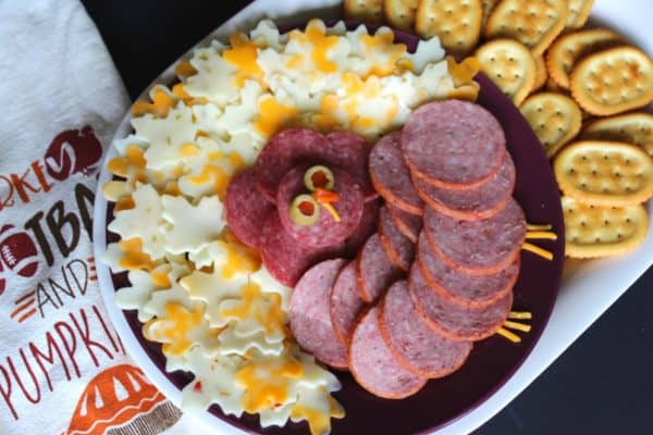Image shows a turkey shaped charcuterie board with salami, cheese  and crackers.