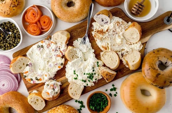 Image shows a cream cheese board with ingredients on and around it.