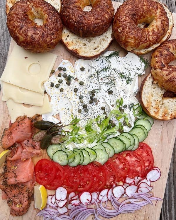 Image shows a cream cheese board with vegetbles, cheese and bagels.