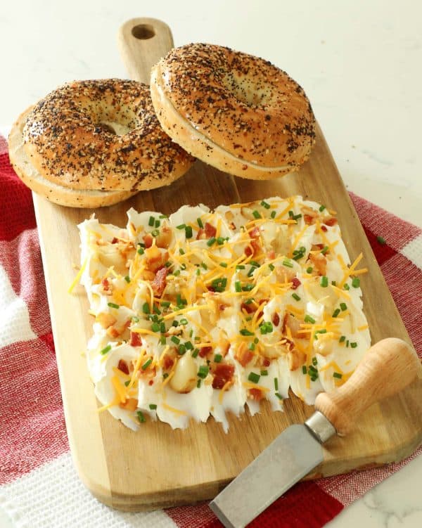 Image showsa cream cheese board with two bagels on top.